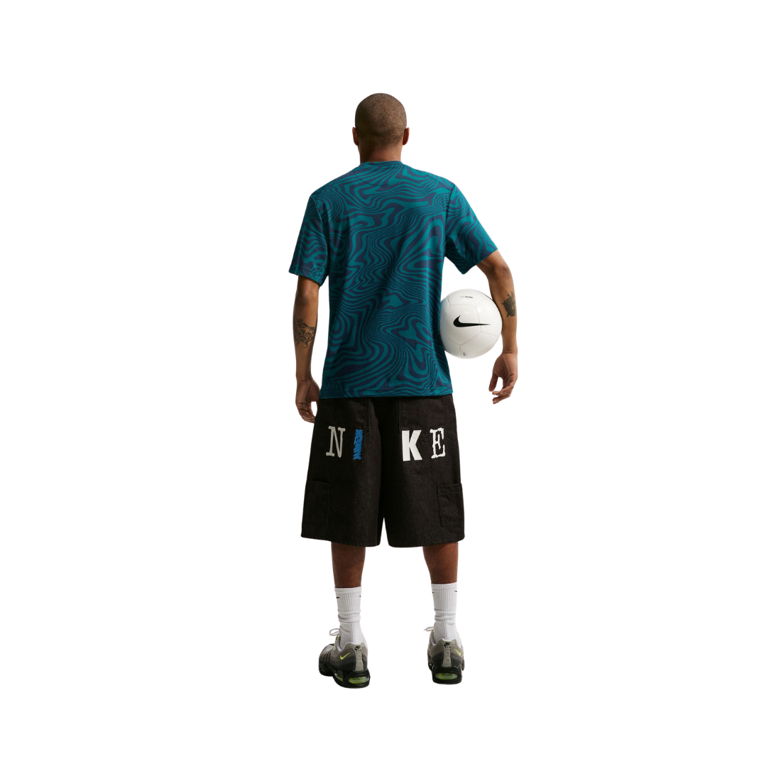 Person wearing a blue shirt and black Nike shorts holding a white ball on a white background