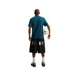 Person wearing a blue shirt and black Nike shorts holding a white ball on a white background