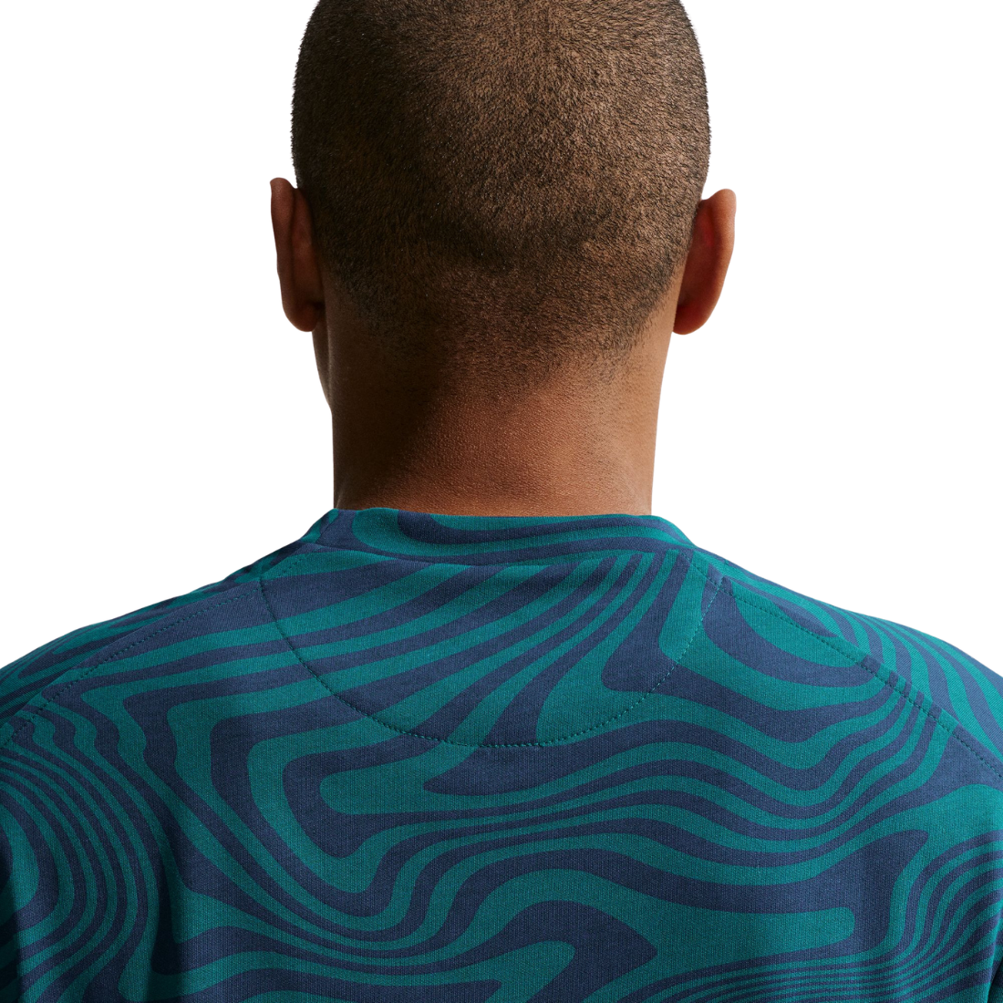 Person wearing a teal and navy patterned shirt on a white background