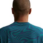 Person wearing a teal and navy patterned shirt on a white background