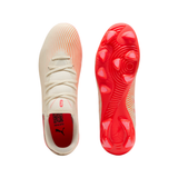 A pair of Puma soccer cleats shown from the top and sole views, featuring a cream-colored upper with subtle orange-red gradient lines and a vibrant red sole with matching red Puma branding.