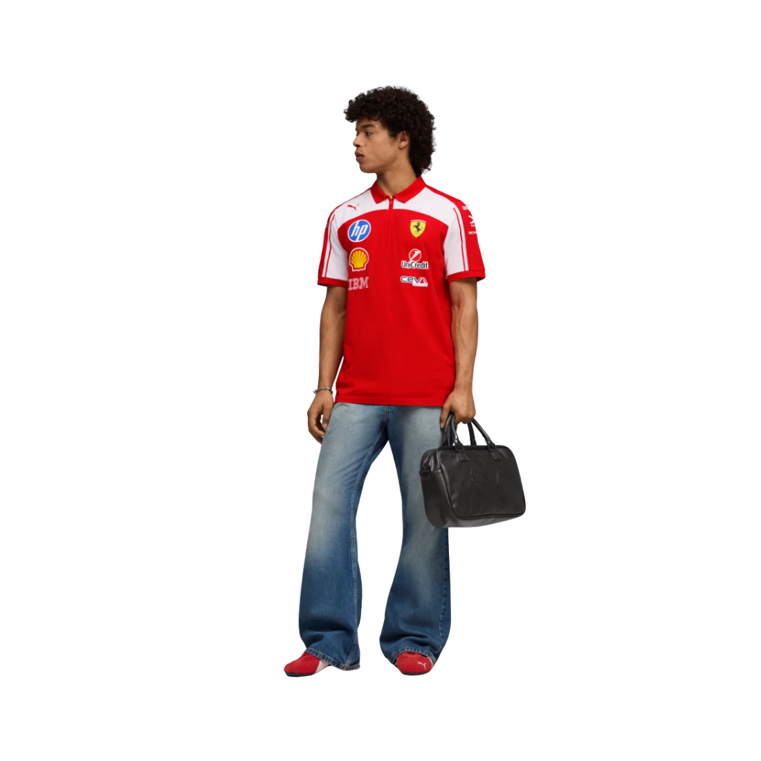 A man wearing a red and white Ferrari polo shirt with various sponsor logos, blue jeans, and red shoes, holding a black duffel bag against a plain white background.