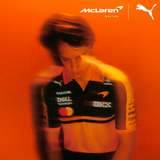 Person wearing PUMA McLaren Racing replica polo jersey in orange and black with sponsor logos