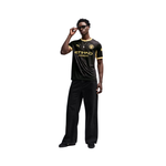 A full-body model wearing a black and yellow Manchester City soccer jersey with 'ETIHAD UNITED' and Puma logos, paired with black trousers and sunglasses, set against a plain white background.