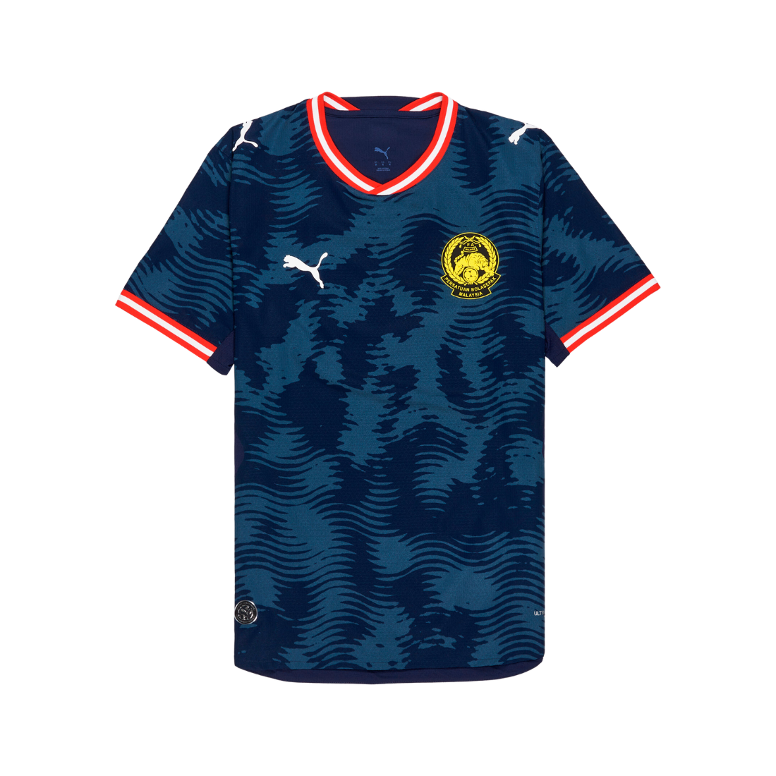 A Puma football jersey with a dark blue and navy wavy pattern, featuring red and white trim on the collar and sleeve cuffs, a white Puma logo on the right chest, and a yellow and blue club crest on the left chest.