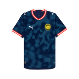 A Puma football jersey with a dark blue and navy wavy pattern, featuring red and white trim on the collar and sleeve cuffs, a white Puma logo on the right chest, and a yellow and blue club crest on the left chest.