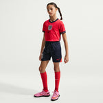 Junior Model wearing a red and navy sports outfit with Nike logo on a white background