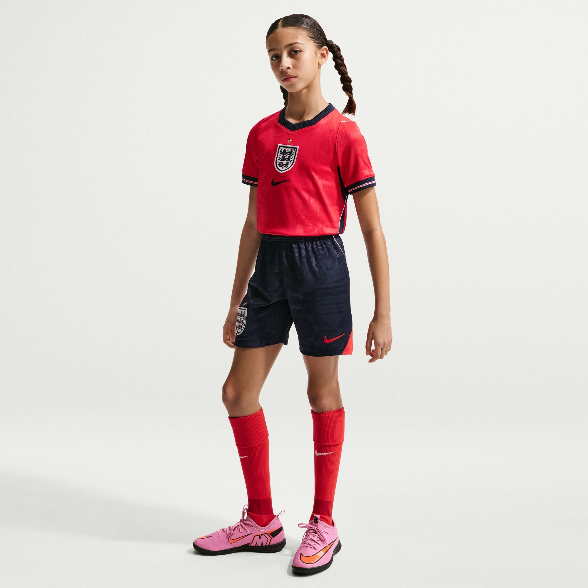Junior Model wearing a red and navy sports outfit with Nike logo on a white background