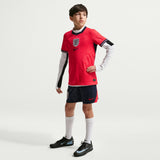Junior Model wearing a red soccer jersey with Nike logo on a white background