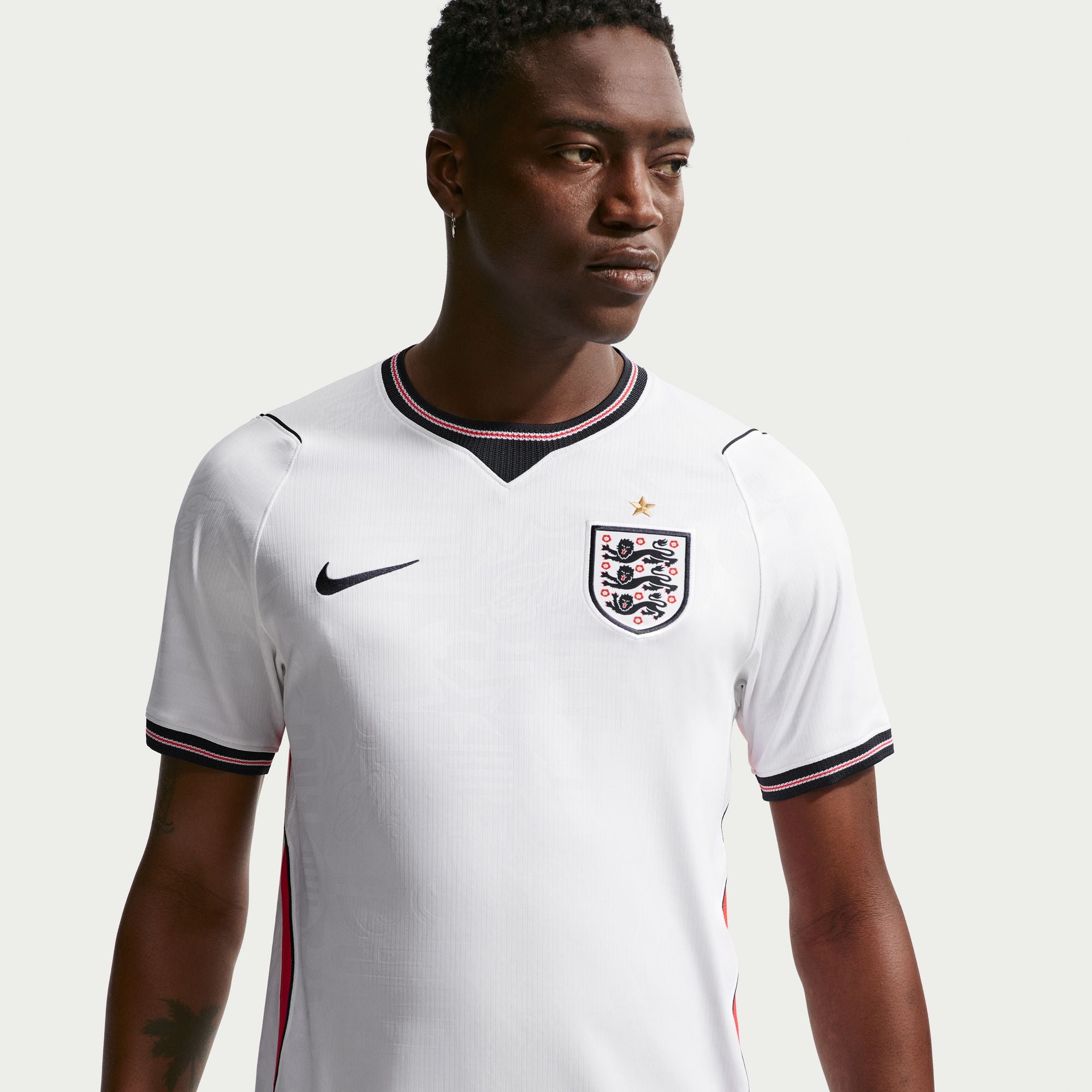 Person wearing a white sports jersey with a logo on a light gray background