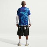 Person wearing a blue patterned shirt and black Nike shorts on a white background