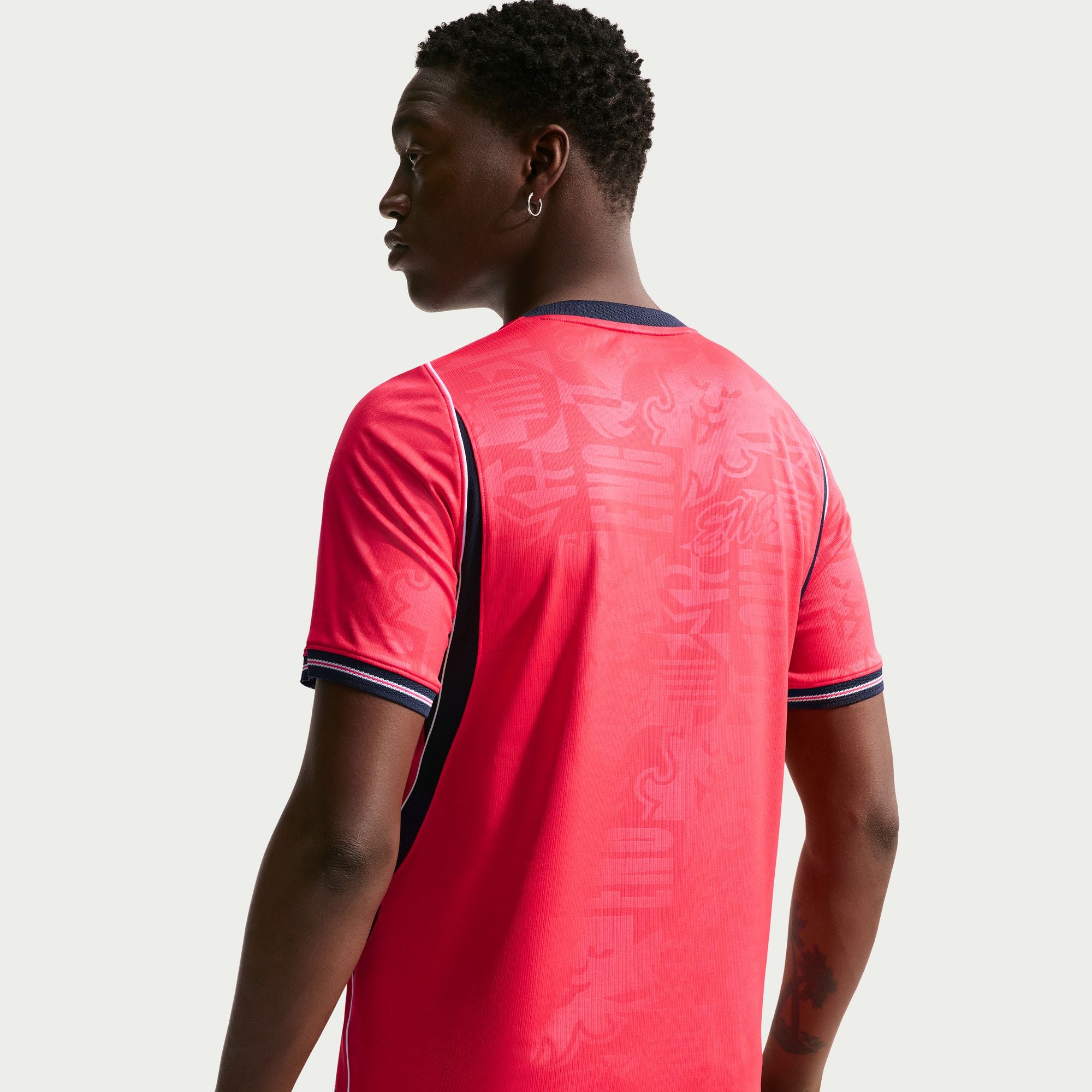 Person wearing a red sports jersey with a subtle pattern on a plain background