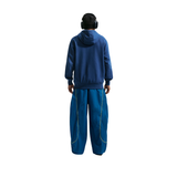 Person wearing a blue tracksuit and headphones on a white background