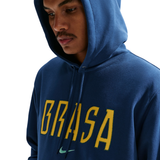 Person wearing a blue hoodie with 'BRASA' printed in yellow on a white background