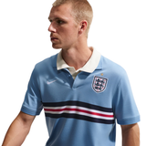 Man wearing a light blue polo shirt with a logo on a white background
