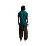 Person wearing a teal shirt and dark pants on a white background