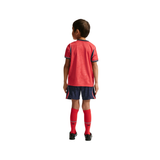 Child wearing a red sports outfit with navy accents on a white background
