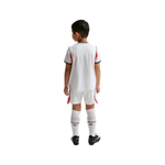 Child wearing a white sports jersey with red accents on a white background