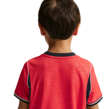 Child wearing a red sports jersey with black accents on a white background