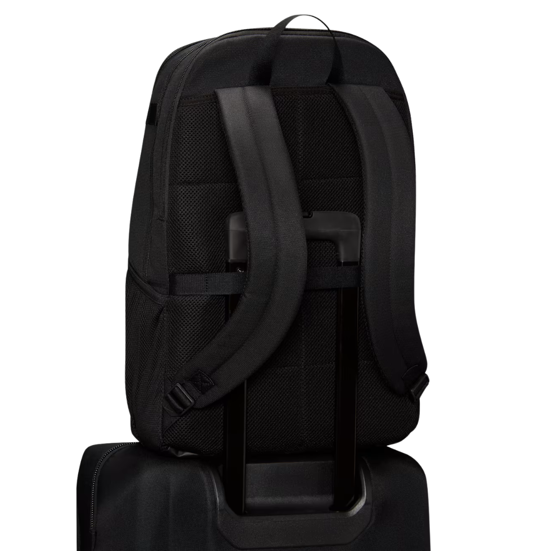 Black backpack shown from the back, resting on top of a rolling suitcase against a plain white background.