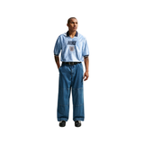 Man wearing a light blue Nike polo shirt and jeans on a white background