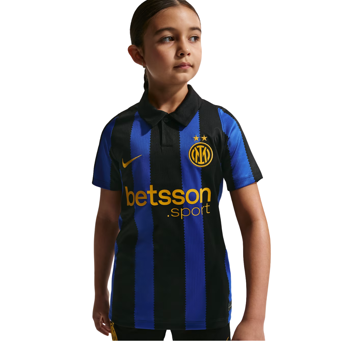 A young girl modeling a short-sleeve polo Inter Milan jersey with blue and black vertical stripes, featuring the yellow Nike swoosh, Inter Milan crest, and Betsson sponsor logo on a white background.
