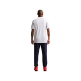 A man viewed from behind wearing a white short-sleeve polo shirt, navy blue pants, and red shoes against a plain white background.