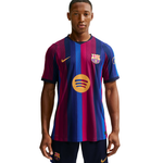A male model wearing a Nike FC Barcelona home soccer jersey with the club crest and Spotify sponsor logo, paired with matching shorts, against a plain white background.