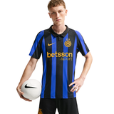 A male model wearing a black and blue vertically striped Inter Milan soccer jersey with a yellow Nike swoosh and Betsson .sport sponsor logo, holding a white soccer ball against a plain white background.