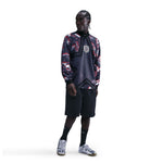 Person wearing a patterned jacket and black shorts on a white background