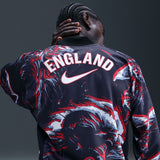 Person wearing a sports jersey with 'England' and Nike logo on a dark background
