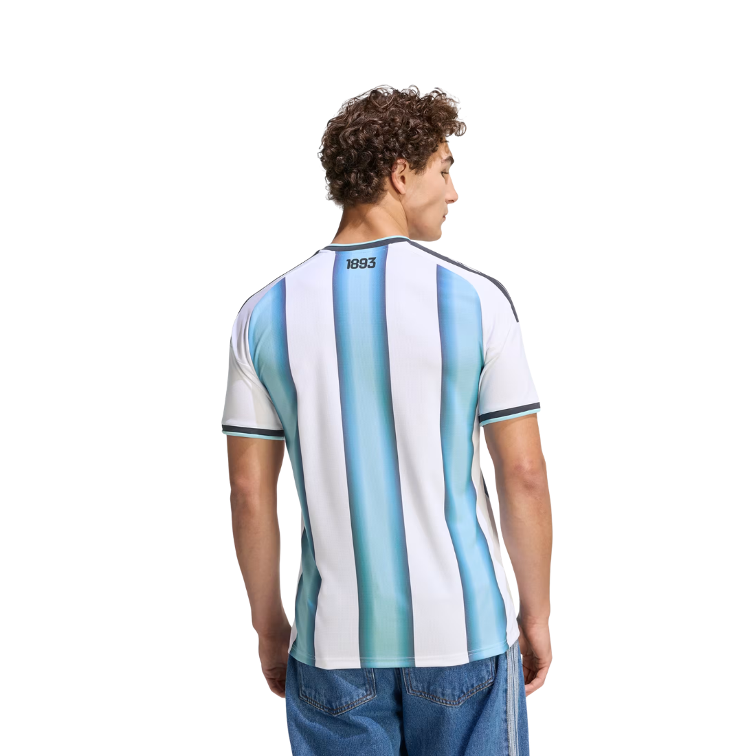 A man viewed from the back wearing a short-sleeve Argentina-style striped jersey with vertical light blue, medium blue, and white stripes, plus dark trim at the collar and sleeve cuffs. The number 1933 is printed near the back neckline.