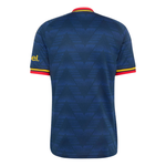 The back of a short-sleeve soccer jersey in dark blue with a subtle geometric pattern, featuring red and yellow trim on the collar and sleeve cuffs, and a yellow 'el.' logo on the right sleeve.