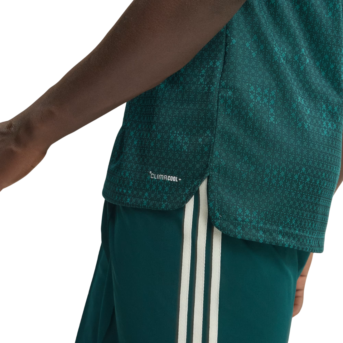 Close-up of a person wearing a dark teal patterned athletic top and matching teal shorts with white side stripes, against a light gray background.