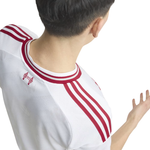 A close-up back view of a person wearing a white Adidas soccer jersey with red three-stripes and a red Adidas logo on the upper left shoulder.