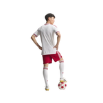 A young male soccer player shown from the back, wearing a white jersey with red trim, red shorts, white socks, and a soccer ball on the ground, isolated on a white background.