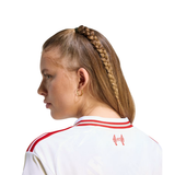 A woman shown from the back and side profile wearing a white sports jersey with red stripes and a red crest on the back, against a plain white background.