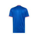 A royal blue short-sleeve soccer jersey shown from the back, featuring a subtle vertical textured pattern and red and white trim on the collar and sleeve cuffs.