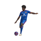 A soccer player in a blue Manchester United kit with red and white accents, kicking a blue and red soccer ball against a solid white background.