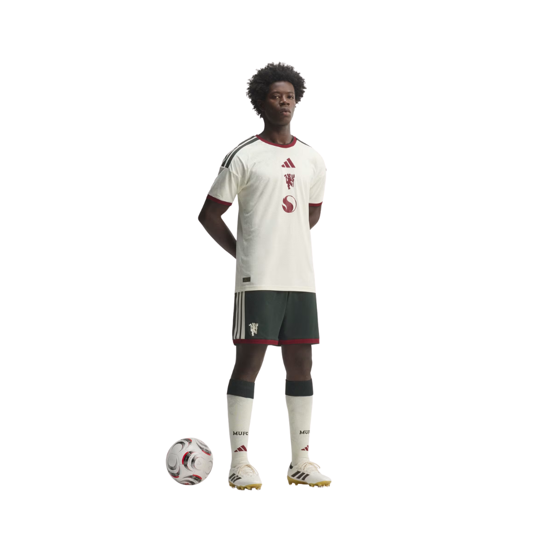 A full-body model wearing a white Adidas soccer jersey with dark green and red trim, matching dark green shorts, white socks, and white soccer cleats, standing next to a soccer ball on a plain white background.