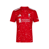 A red short-sleeve soccer jersey with white accents, featuring the Adidas logo, Liverpool FC crest, and 'standard chartered' sponsor logo.