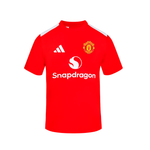 A red short-sleeve soccer jersey Junior with white shoulder stripes, featuring the Manchester United crest on the left chest, the white Adidas logo on the right chest, and the white Snapdragon sponsor logo across the center.